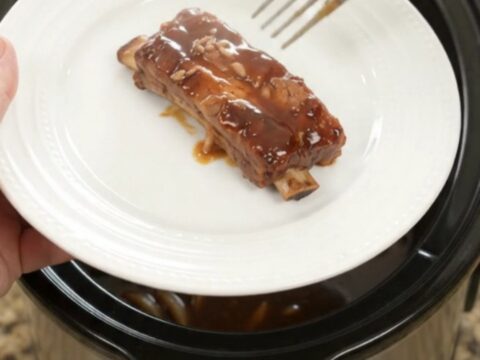 Slow cooker full of glazed root beer molasses pork ribs with caramelized onions