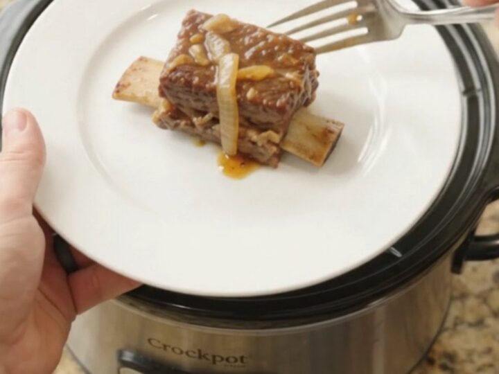 Beef short ribs glazed in maple-bourbon barbecue sauce with caramelized onions in a slow cooker