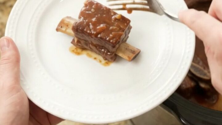 Slow cooker short ribs with pineapple rings and BBQ sauce, glistening in the pot.