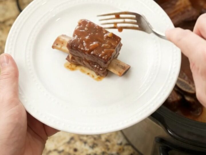 Slow cooker short ribs with pineapple rings and BBQ sauce, glistening in the pot.