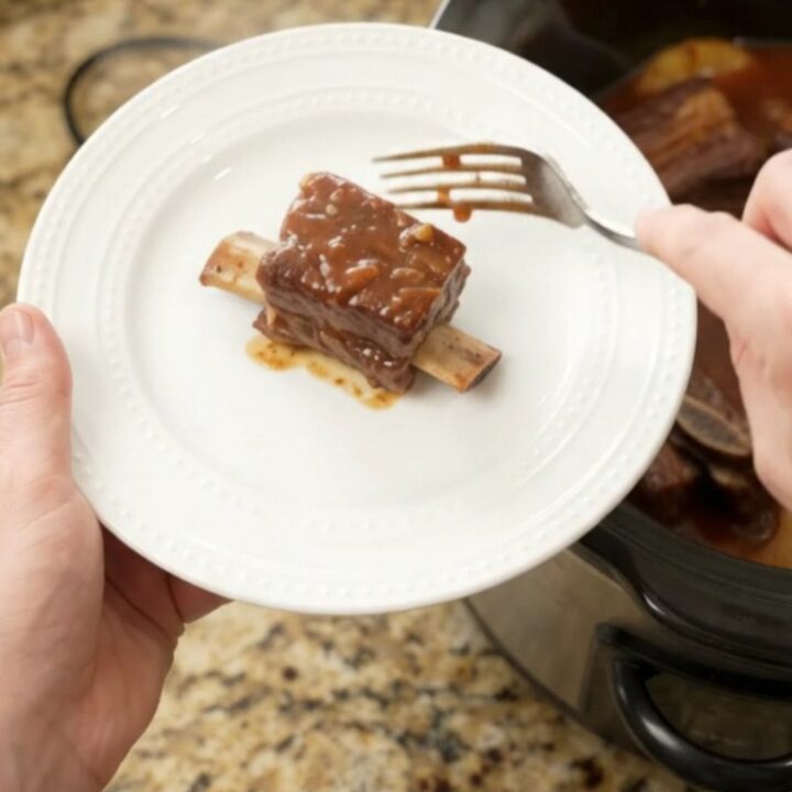 Slow cooker short ribs with pineapple rings and BBQ sauce, glistening in the pot.