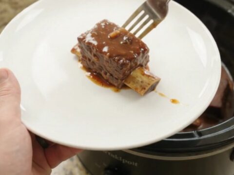 Slow cooker full of glazed beef short ribs in barbecue sauce with chipotle peppers