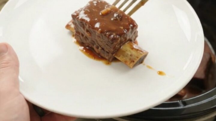 Slow cooker full of glazed beef short ribs in barbecue sauce with chipotle peppers