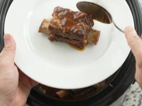 Slow-cooked beef short ribs glazed with smoky chipotle honey barbecue sauce in a black slow cooker