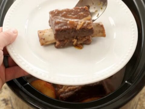 Slow-cooked beef short ribs glazed with honey hickory BBQ and peaches in a Crockpot