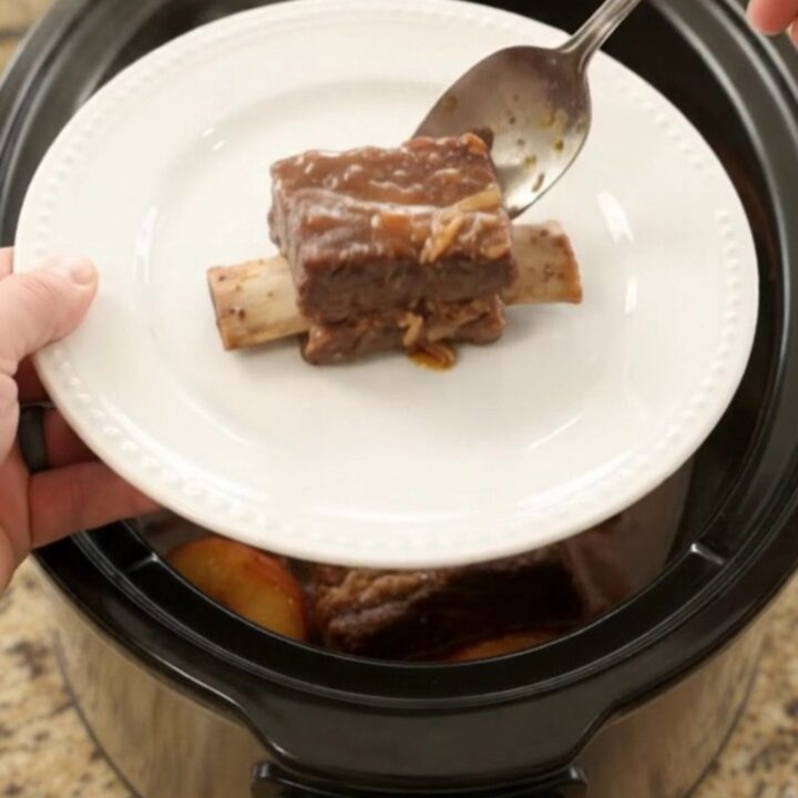 Slow-cooked beef short ribs glazed with honey hickory BBQ and peaches in a Crockpot