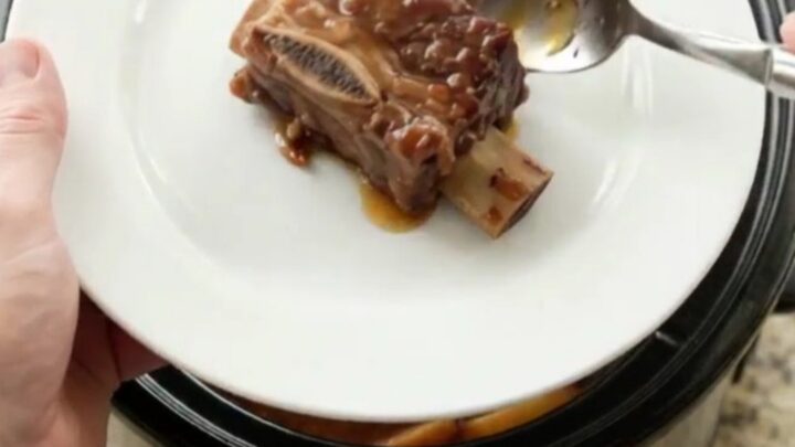 Slow cooker cherry cola BBQ short ribs glistening with sticky sauce, garnished with fresh cherries