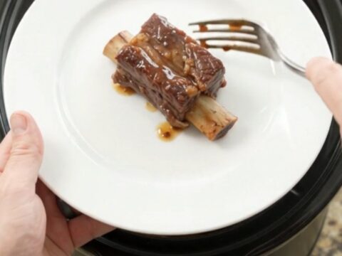Slow-cooked beef short ribs glistening with cherry-cola barbecue sauce in a black crockpot