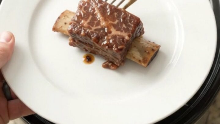 Slow cooker beef short ribs coated in glossy honey hickory BBQ sauce with garlic and rosemary