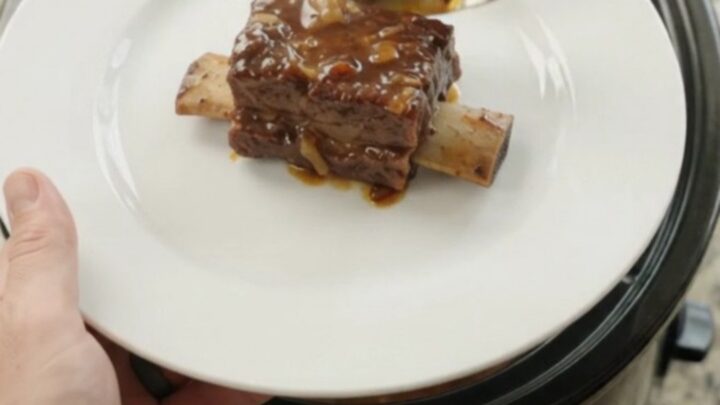 Glossy slow-cooked beef short ribs in a dark molasses BBQ sauce in a black crockpot