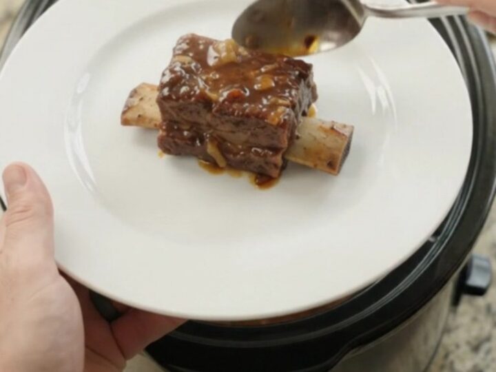 Glossy slow-cooked beef short ribs in a dark molasses BBQ sauce in a black crockpot