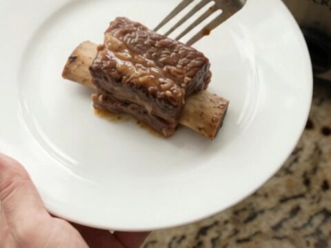 Sweet Vidalia Molasses Beef Short Ribs in a slow cooker, glistening with dark sauce and topped with caramelized onions.