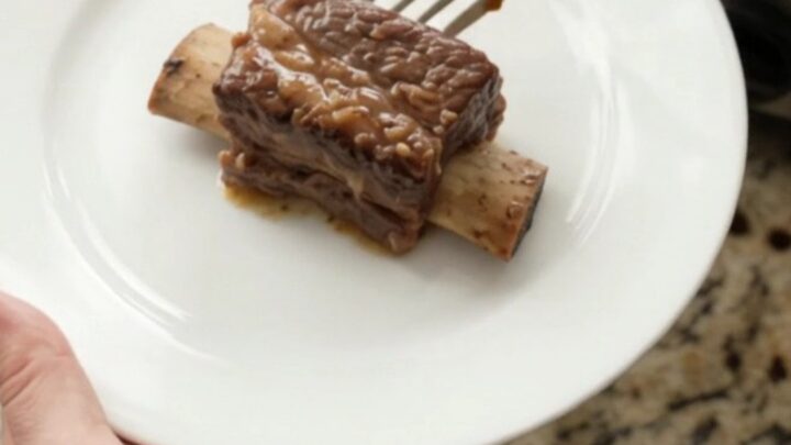 Sweet Vidalia Molasses Beef Short Ribs in a slow cooker, glistening with dark sauce and topped with caramelized onions.