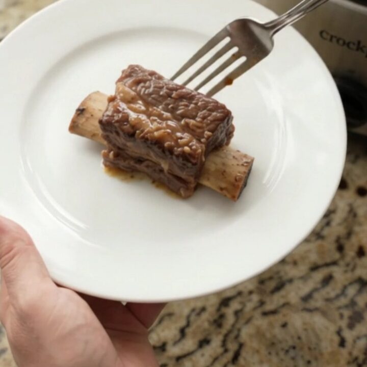 Sweet Vidalia Molasses Beef Short Ribs in a slow cooker, glistening with dark sauce and topped with caramelized onions.