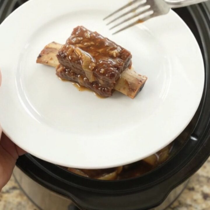Slow cooker beef short ribs glazed in honey hickory BBQ sauce with caramelized Vidalia onions