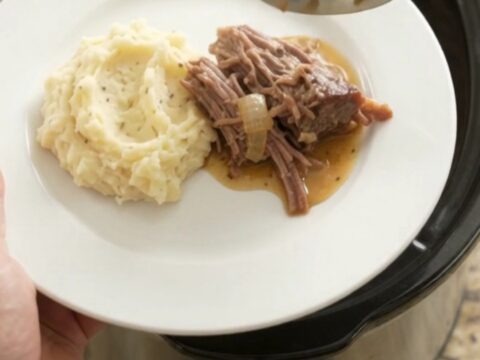 Shredded beef chuck roast with mushrooms in a buttery jus in a slow cooker.