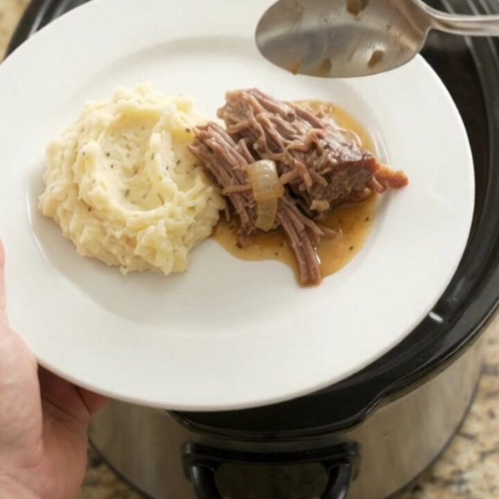 Shredded beef chuck roast with mushrooms in a buttery jus in a slow cooker.