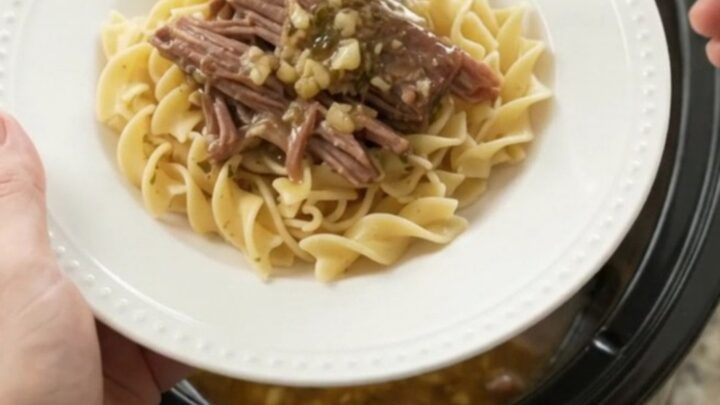 Shredded pepperoncini ranch garlic butter chuck roast in a slow cooker, with steamy gravy and golden peppers.