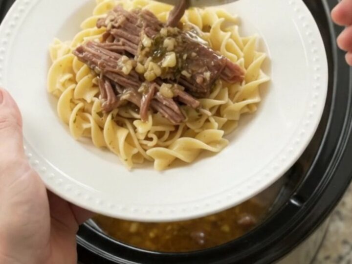 Shredded pepperoncini ranch garlic butter chuck roast in a slow cooker, with steamy gravy and golden peppers.