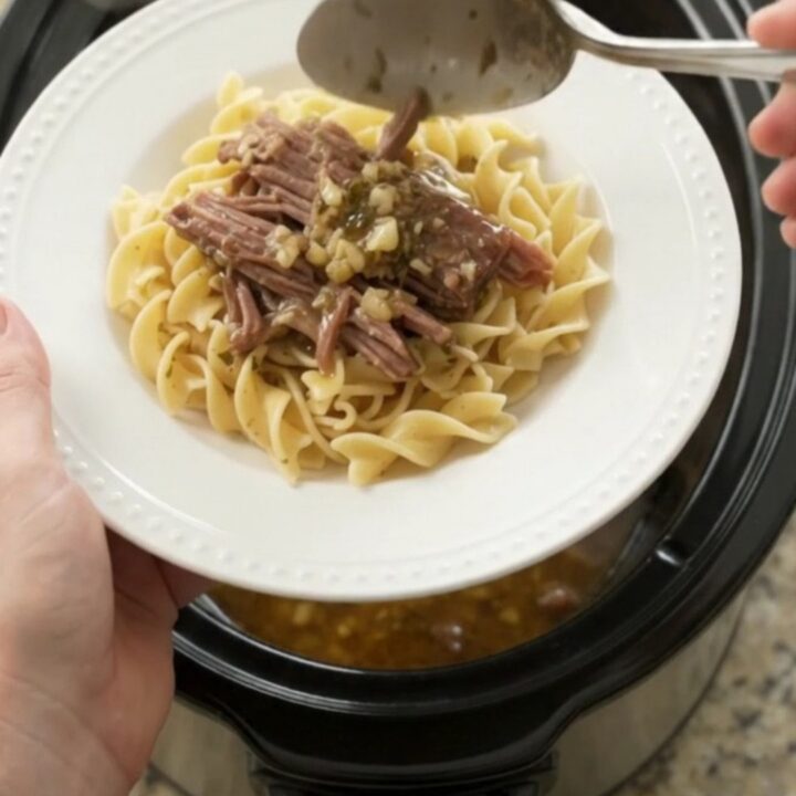 Shredded pepperoncini ranch garlic butter chuck roast in a slow cooker, with steamy gravy and golden peppers.