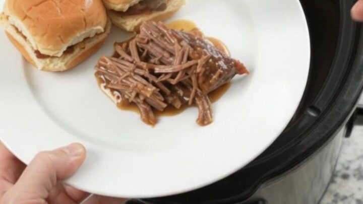 Shredded pepperoncini ranch chuck roast in a slow cooker with glossy gravy and pepperoncini