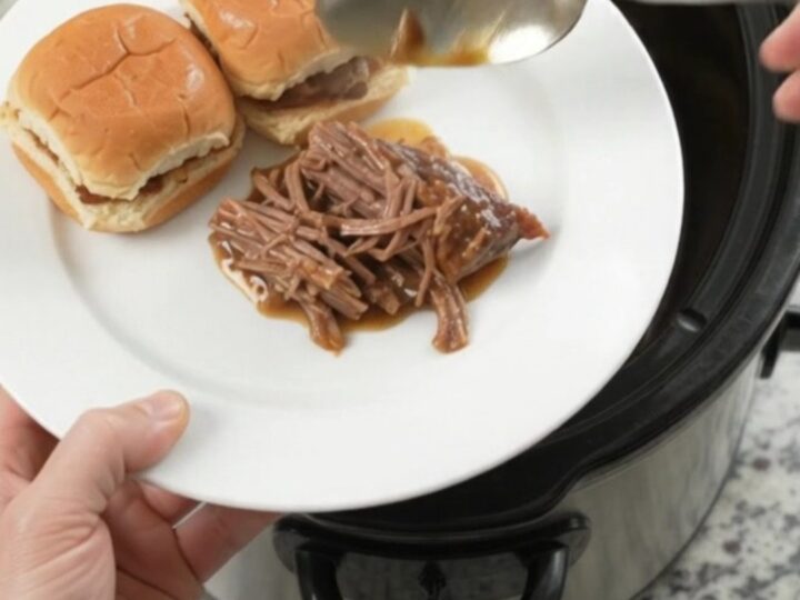 Shredded pepperoncini ranch chuck roast in a slow cooker with glossy gravy and pepperoncini