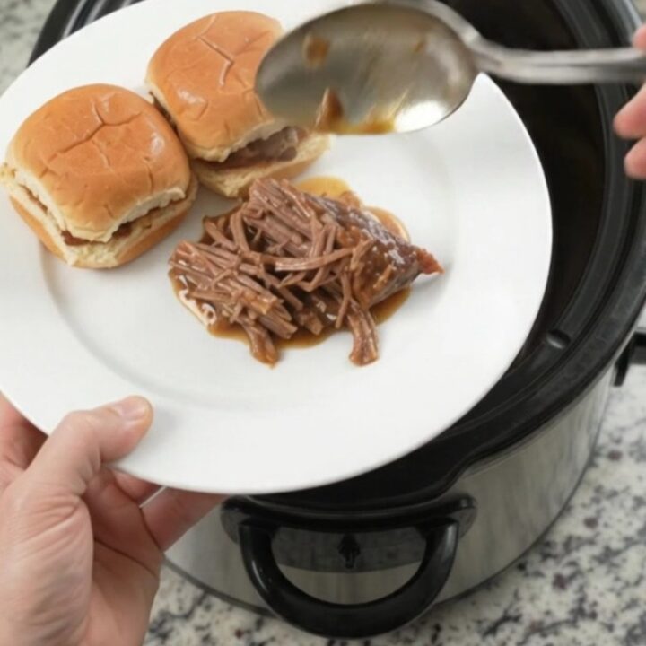 Shredded pepperoncini ranch chuck roast in a slow cooker with glossy gravy and pepperoncini