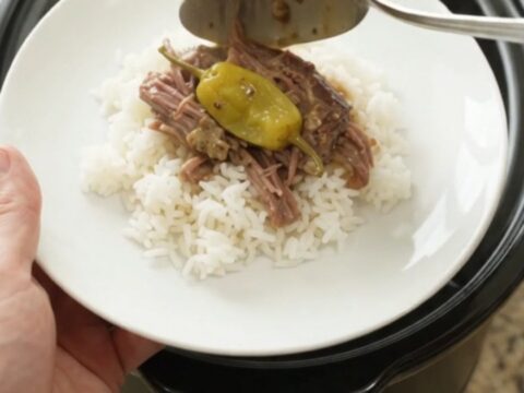 Shredded pepperoncini ranch chuck roast in a slow cooker with creamy sauce