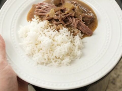 Slow cooker chuck roast with mushrooms and creamy Dijon gravy in a black crockpot