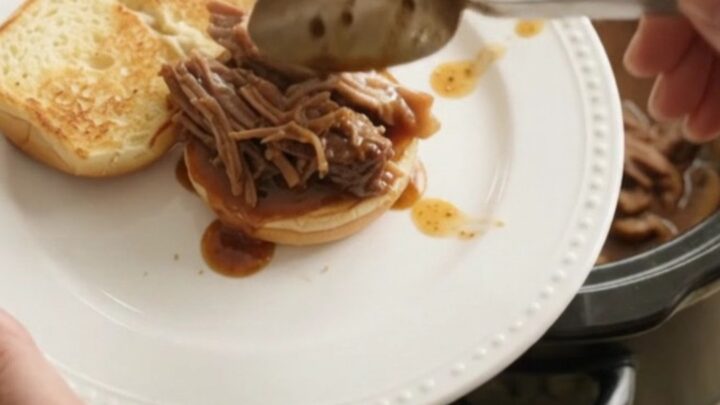 Shredded beef chuck roast in a slow cooker with mushrooms and brown gravy