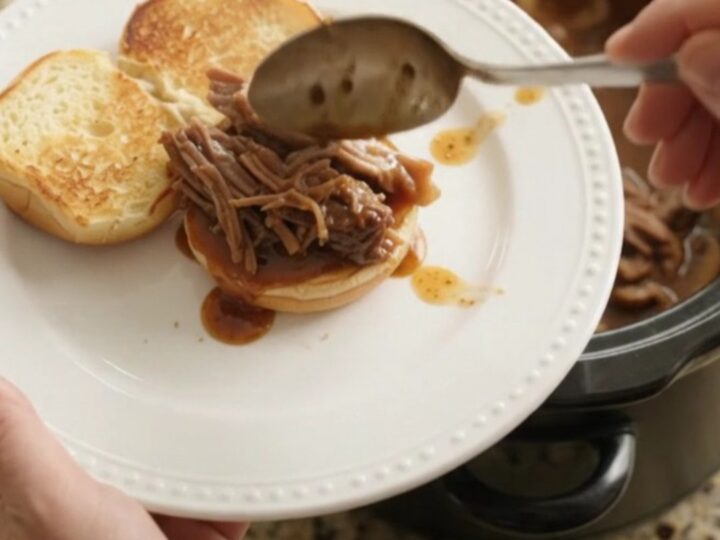 Shredded beef chuck roast in a slow cooker with mushrooms and brown gravy