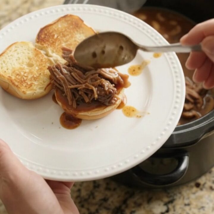 Shredded beef chuck roast in a slow cooker with mushrooms and brown gravy