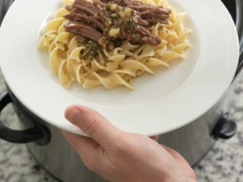 Shredded beef chuck roast with pearl onions in a rich stout gravy in a slow cooker