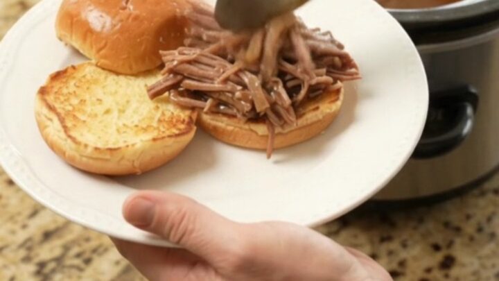 Fall-apart shredded beef chuck roast in rich brown gravy with caramelized onions in a slow cooker
