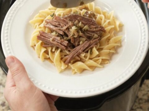Slow-cooker garlic butter chuck roast with rosemary and thyme in a black crockpot
