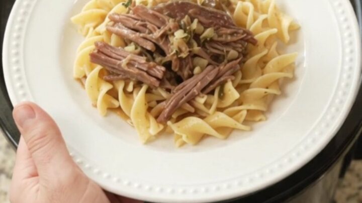 Slow-cooker garlic butter chuck roast with rosemary and thyme in a black crockpot