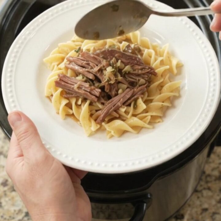 Slow-cooker garlic butter chuck roast with rosemary and thyme in a black crockpot