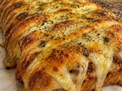 A golden-brown potato roll stromboli on a marble counter, sliced to reveal melted mozzarella.