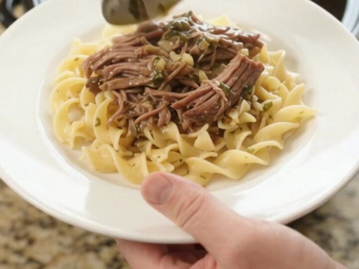 Shredded beef chuck roast with potatoes and carrots in a slow cooker, topped with butter gravy