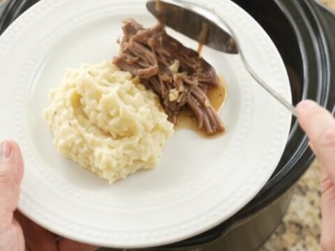 Shredded beef chuck roast with portobello mushrooms and golden butter jus in a slow cooker