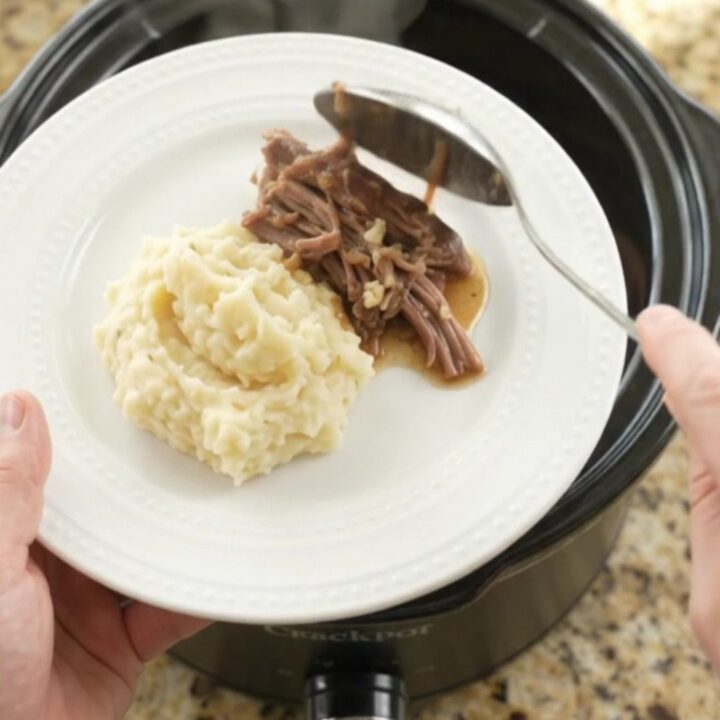 Shredded beef chuck roast with portobello mushrooms and golden butter jus in a slow cooker