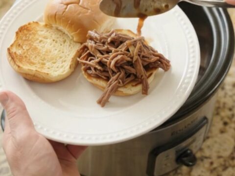 Shredded chuck roast in rich gravy with sweet peppers and onions in a slow cooker