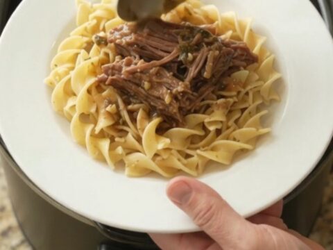 Shredded beef chuck roast with peppers and onions in a slow cooker