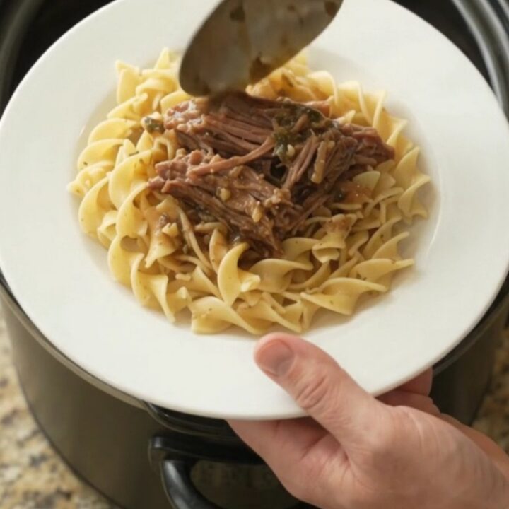 Shredded beef chuck roast with peppers and onions in a slow cooker