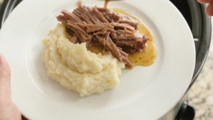 Slow cooker brisket with pepperoncini and butter sauce in a black crockpot