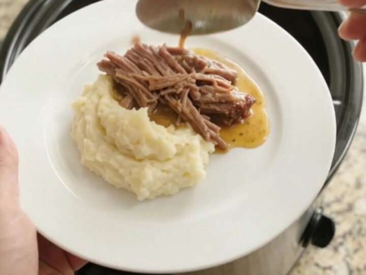 Slow cooker brisket with pepperoncini and butter sauce in a black crockpot