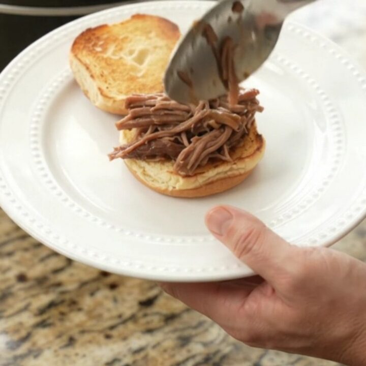 Slow-cooker beef brisket with mushrooms in rich gravy, served on a white plate