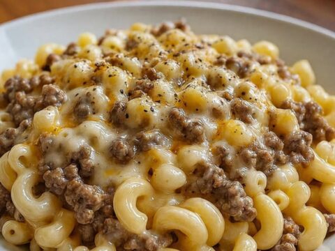 A close-up of creamy ranch beef macaroni with long, melted cheese strings being pulled up by a fork.