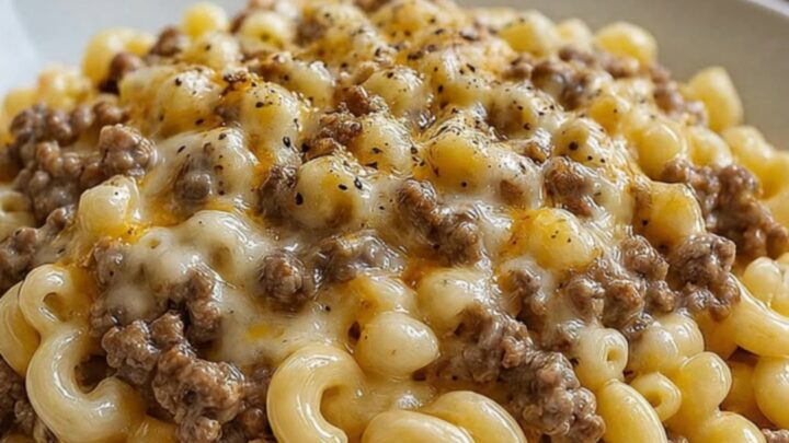 A close-up of creamy ranch beef macaroni with long, melted cheese strings being pulled up by a fork.