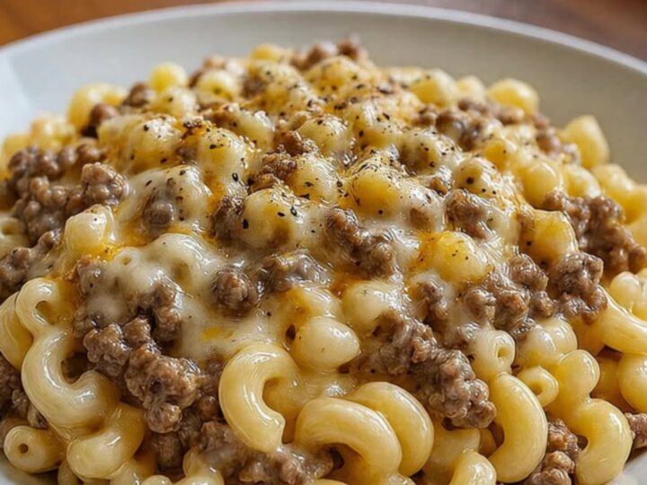 A close-up of creamy ranch beef macaroni with long, melted cheese strings being pulled up by a fork.